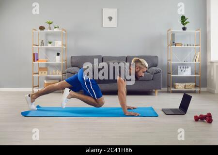 Allenatore sportivo in forma facendo scalatori di montagna allenarsi online a casa Foto Stock