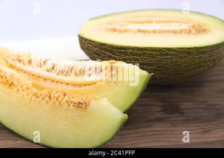 Fette di melone Piel de Sapo su un tagliere di legno e sfondo bianco con spazio per la copia Foto Stock