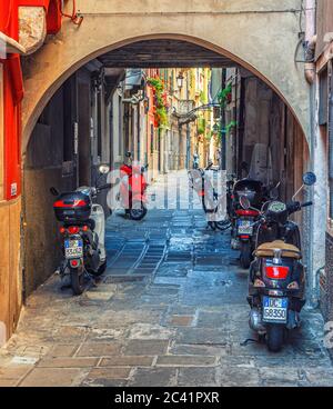 Chioggia, 16 settembre 2019: Moto Vespa e moto scooter in un arco di strada acciottolata nel centro storico della città, Regione Veneto Foto Stock