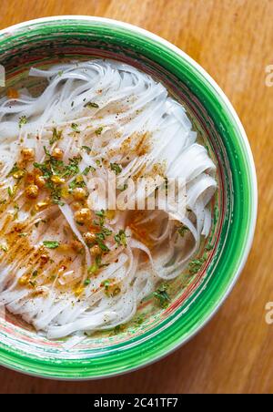 Zuppa di ramen con tagliatelle di riso sparate direttamente dall'alto sul tavolo nel cafe' Vietnamita. Cucina Asiatica tradizionale cucinata con erbe e spezie per Dinner.De Foto Stock
