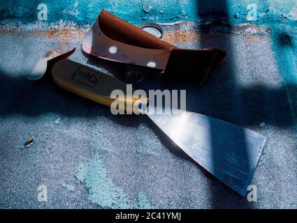 Primo piano di carta abrasiva e di un coltello per stucco con luce naturale Foto Stock