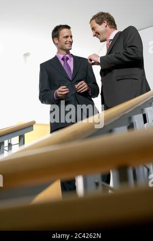 Due uomini d'affari stanno chiacchierando in cima a una scala - corridoio - colleghi Foto Stock