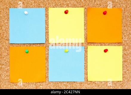 Sei note adesive vuote di diversi colori, attaccate alla bacheca in sughero. Foto Stock