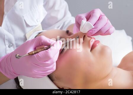 Il medico-cosmetologo fa la procedura di trattamento di Coupérose della pelle facciale di una bella, giovane donna in un salone di bellezza.Cosmetology e. Foto Stock