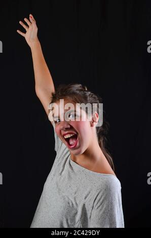 Allegra ragazza adolescente, gridando forte per esprimere gioia, studio girato su sfondo nero