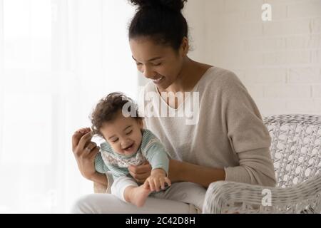 Carina bambina seduta su giri sorridenti della madre Foto Stock