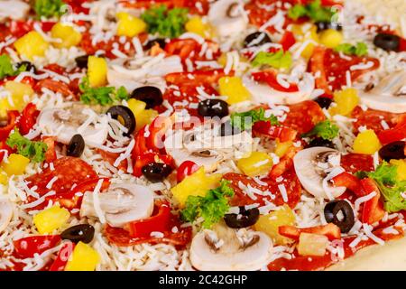 Pizza rotonda cruda con funghi, pepperoni e ananas. Primo piano. Foto Stock