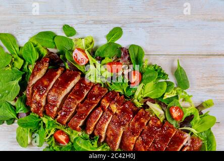 Filetto di maiale al barbecue o filetto su foglie verdi con pomodoro. Foto Stock