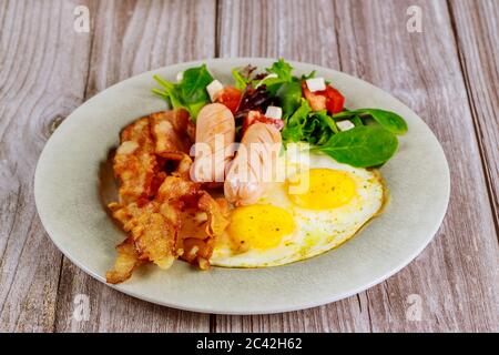 franche di pollo, uova fritte, pancetta e insalata su tavolo di legno per la colazione. Foto Stock