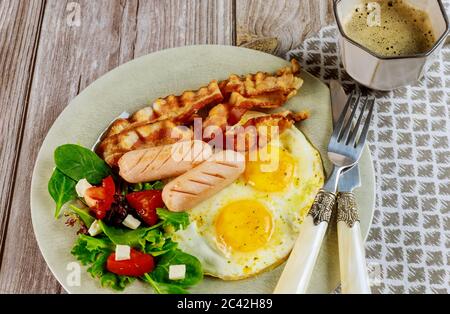 Gustosa colazione con uova, salsicce, pancetta, pane tostato e tazza di caffè. Foto Stock