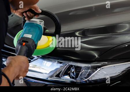 Auto detailing.Man mano che tiene e lucidare la cera auto.lucidando auto. Foto Stock