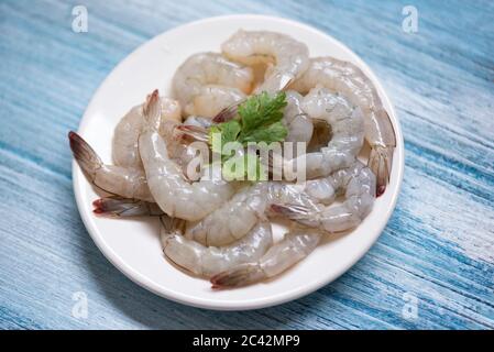 Gamberi freschi o gamberi, pesce al riparo / gamberetti crudi su piatto bianco e sfondo di legno per cucinare Foto Stock