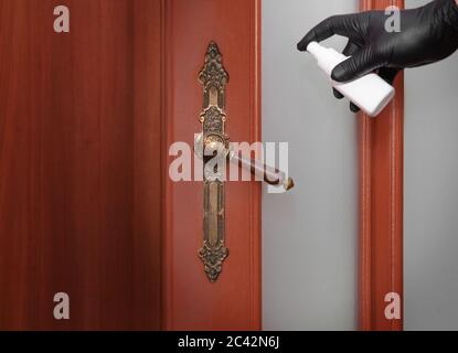 Disinfezione con pomolo della porta per prevenire l'infezione virale durante la pandemia COVID. Foto Stock