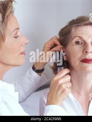 Il medico femminile esamina l'orecchio di una donna anziana - visita del medico - esame Foto Stock