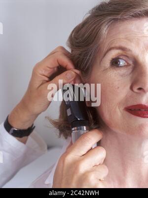 Il medico femminile esamina l'orecchio di una donna anziana - visita del medico - esame Foto Stock