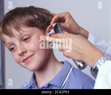 Dottore studia l'orecchio di un ragazzino - visita medica - esame Foto Stock