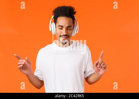 Uomo che gode battiti impressionanti. Attraente moderno hipster afro-americano ragazzo con taglio di capelli afro, baffi, chiudere gli occhi batterming con le dita e ascoltare Foto Stock