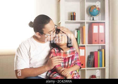 Padre asiatico confortando la sua figlia triste e piangente, papà singolo e bambina insieme Foto Stock