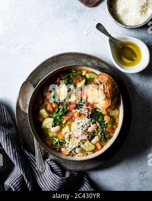 Ciotola di minestrone con parmigiano grattugiato e pane tostato all'aglio. Foto Stock