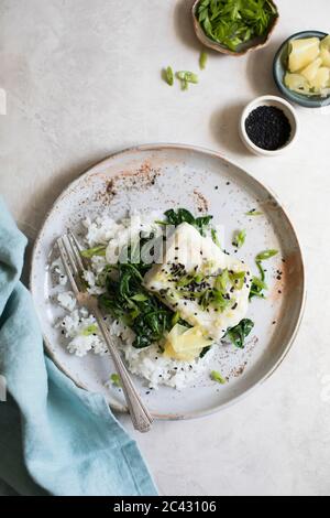 Filetto di pesce bianco al forno, spinaci saltati, fagioli verdi e cipolle primaverili su un letto di riso. Foto Stock