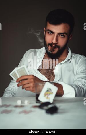 Ritratto di un giocatore esperto. Giovane giocatore che beve sigaro e whisky. Foto Stock