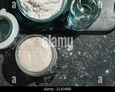 Antipasto di pasta di grano. Vaso in vetro con base di pasta acida su sfondo scuro, spazio per la copia. Foto Stock