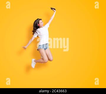 giovane donna che salta mentre ascolta la musica con le cuffie Foto Stock