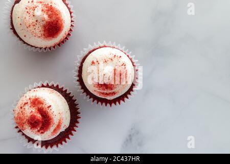 Vista dall'alto di tre Cupcake di velluto rosso su marmo Foto Stock