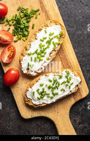 Croccante con formaggio cremoso, erba cipollina e pomodori sul tavolo da cucina. Vista dall'alto. Foto Stock
