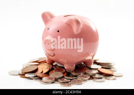 Risparmiare denaro, pianificazione finanziaria delle finanze personali e di essere thrifty concetto tema con una rosa piggy banca seduta su un mucchio di bronzo e argento colo Foto Stock