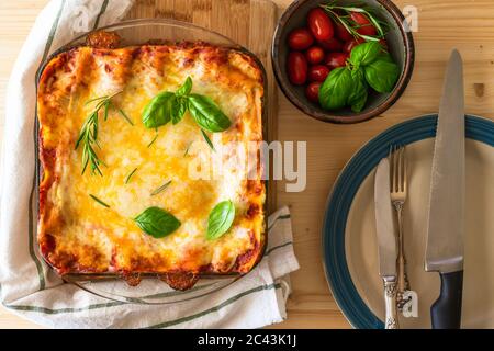 Lasagne di spinaci con pomodori, rosmarino e basilico. Deliziosa lasagna di spinaci fatta in casa con erbe e pomodori freschi da vicino, vista dall'alto Foto Stock
