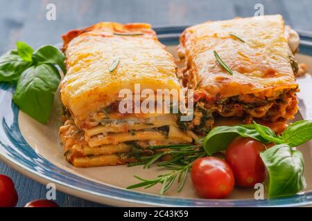 Lasagna spinaci. Deliziosa lasagna di spinaci fatta in casa servita con pomodori freschi e basilico da vicino su un piatto Foto Stock