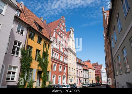 15 giugno 2020, Meclemburgo-Pomerania occidentale, Stralsund: Vista di una fila di case nel centro storico di Stralsund, nella via dei traghetti. La città anseatica di Stralsund, menzionata per la prima volta nel 1234, è uno dei magneti turistici del Meclemburgo-Vorpommern a causa degli oltre 500 edifici elencati, la maggior parte dei quali è stata ampiamente restaurata negli ultimi anni con la società di trustee revelopment Stadterneuerungsgesellschaft Stralsund mbH (SES). Nel giugno 2002, il centro storico medievale di Stralsund è stato incluso nella lista dei siti Patrimonio dell'Umanità dell'UNESCO insieme alla Città anseatica di Wismar. Foto Stock