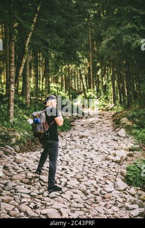 Uomo con zaino trekking nella foresta di pietra il sentiero percorso Foto Stock