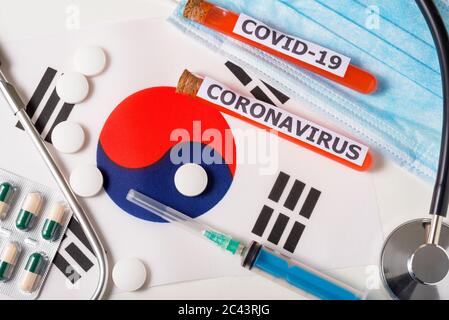 Coronavirus, concetto nCoV. Vista dall'alto maschera respiratoria protettiva, stetoscopio, siringa, pillole sulla bandiera della Corea del Sud. Un nuovo focolaio del cinese c Foto Stock