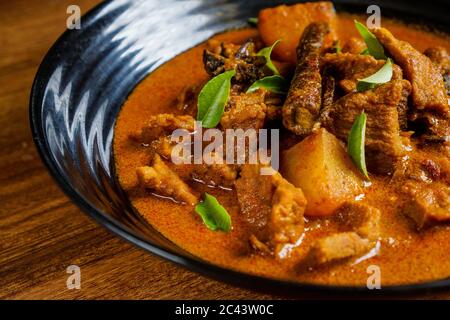 Carne di agnello cotta al curry con patate e spezie e guarnita con foglie di curry. Foto Stock