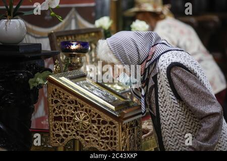 Snagov, Romania - 21 giugno 2020: La donna anziana che indossa una maschera Covid-19 prega fuori di una chiesa ortodossa cristiana. Foto Stock