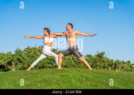 Coppia matura che fa yoga sul prato al sole insieme Foto Stock
