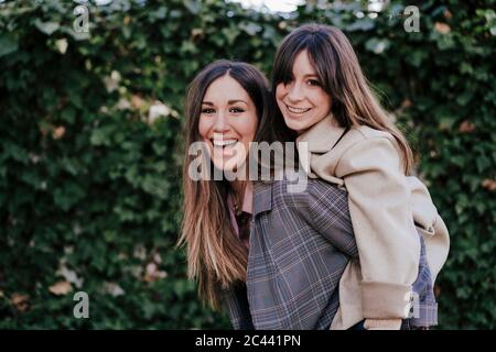 Poertrait di ridere donna dando al suo amico un giro piggyback Foto Stock