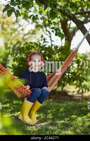 Ragazza con smartphone e cuffie in amaca per ascoltare musica Foto Stock