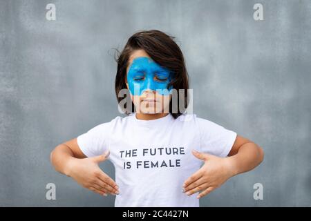 Ritratto di ragazzo con maschera blu dipinta sul viso con t-shirt con impronta 'il futuro è femminile' Foto Stock