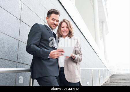 Una buona coppia di lavoro che utilizza un tablet digitale mentre si sta sui gradini Foto Stock