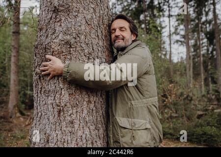 Tronco di albero hugging escursionista maturo Foto Stock