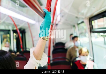 Giovane donna che indossa guanti protettivi in autobus pubblico, Spagna Foto Stock