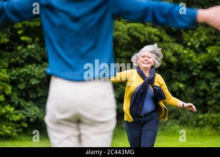 Ritratto di felice anziana che corre alla figlia adulta in un parco Foto Stock