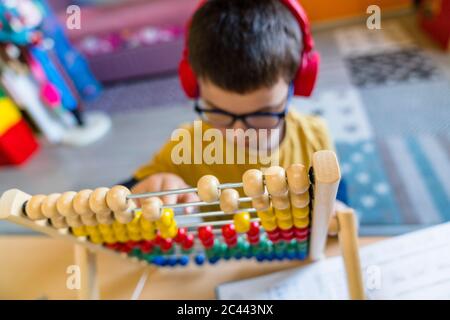 Ragazzo che calcola con abaco mentre si siede a casa Foto Stock