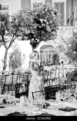 Donna in abito bianco è in piedi fuori a tavoli elegantemente posati Foto Stock