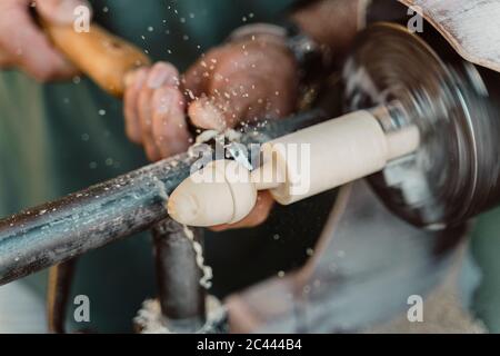 Close-up di falegname azienda scalpello durante la sagomatura del legno in officina Foto Stock