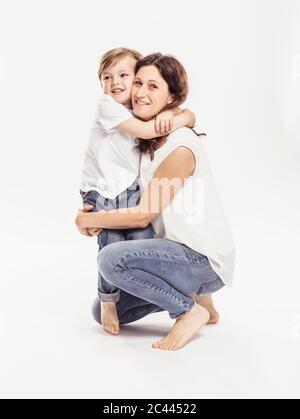 Ritratto di madre felice e suo figlio che si abbracciano di fronte a sfondo bianco Foto Stock