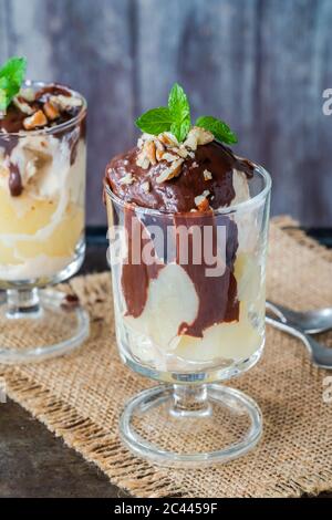 Dessert con gelato con pere in camicia e salsa al cioccolato guarnita con menta fresca Foto Stock